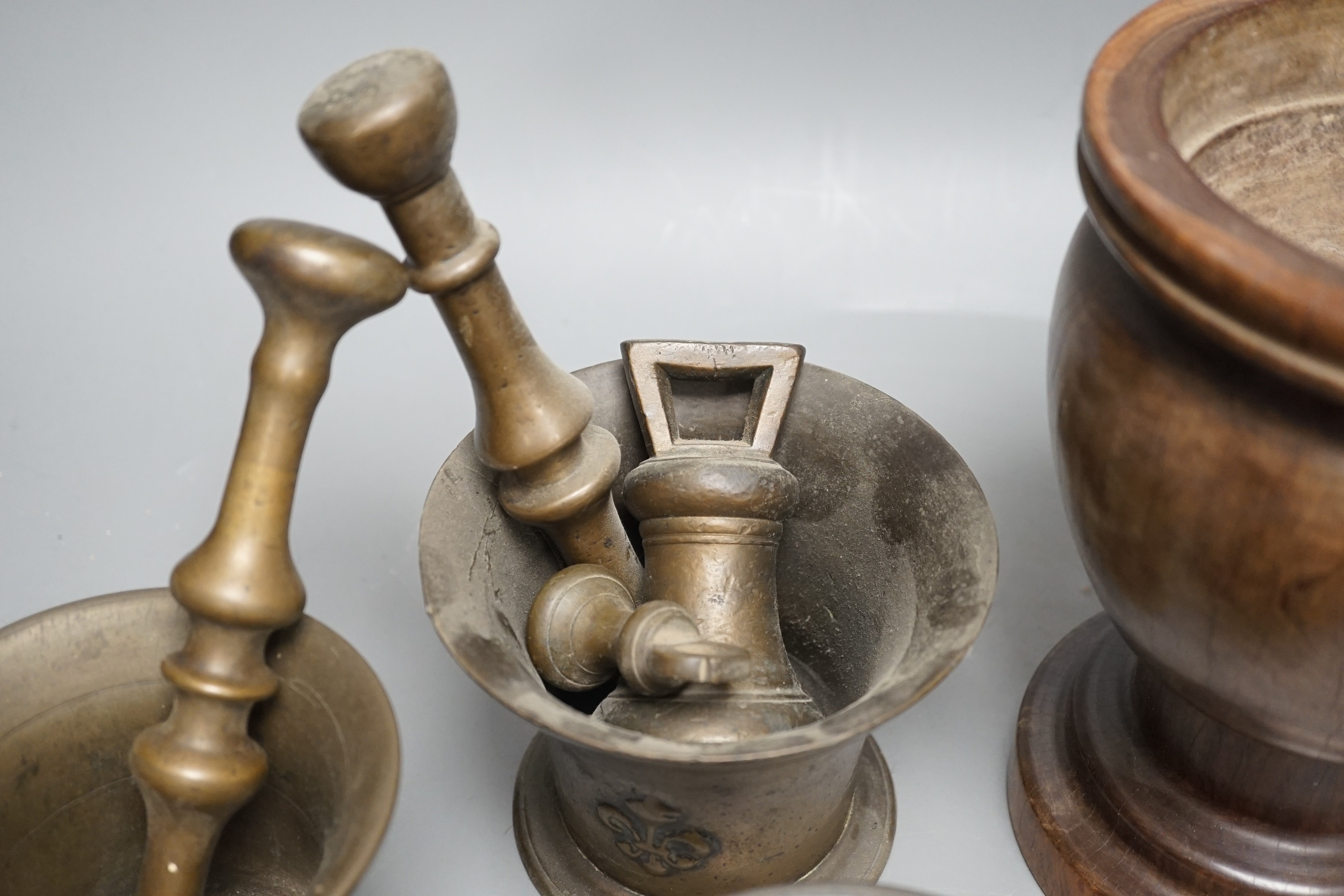 Three bell metal mortars, two pestles, a turned lignum vitae mortar and three postal weights, urn height 20cm